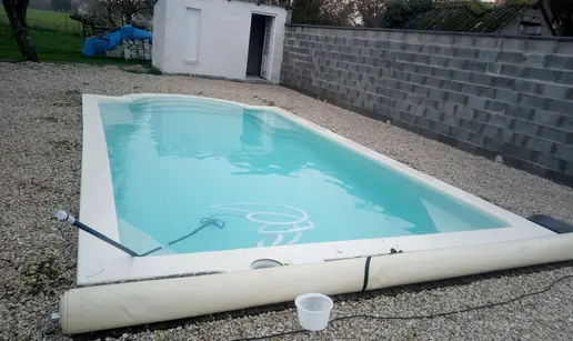 Nettoyage de la piscine avec une épuisette et des produits chimiques.